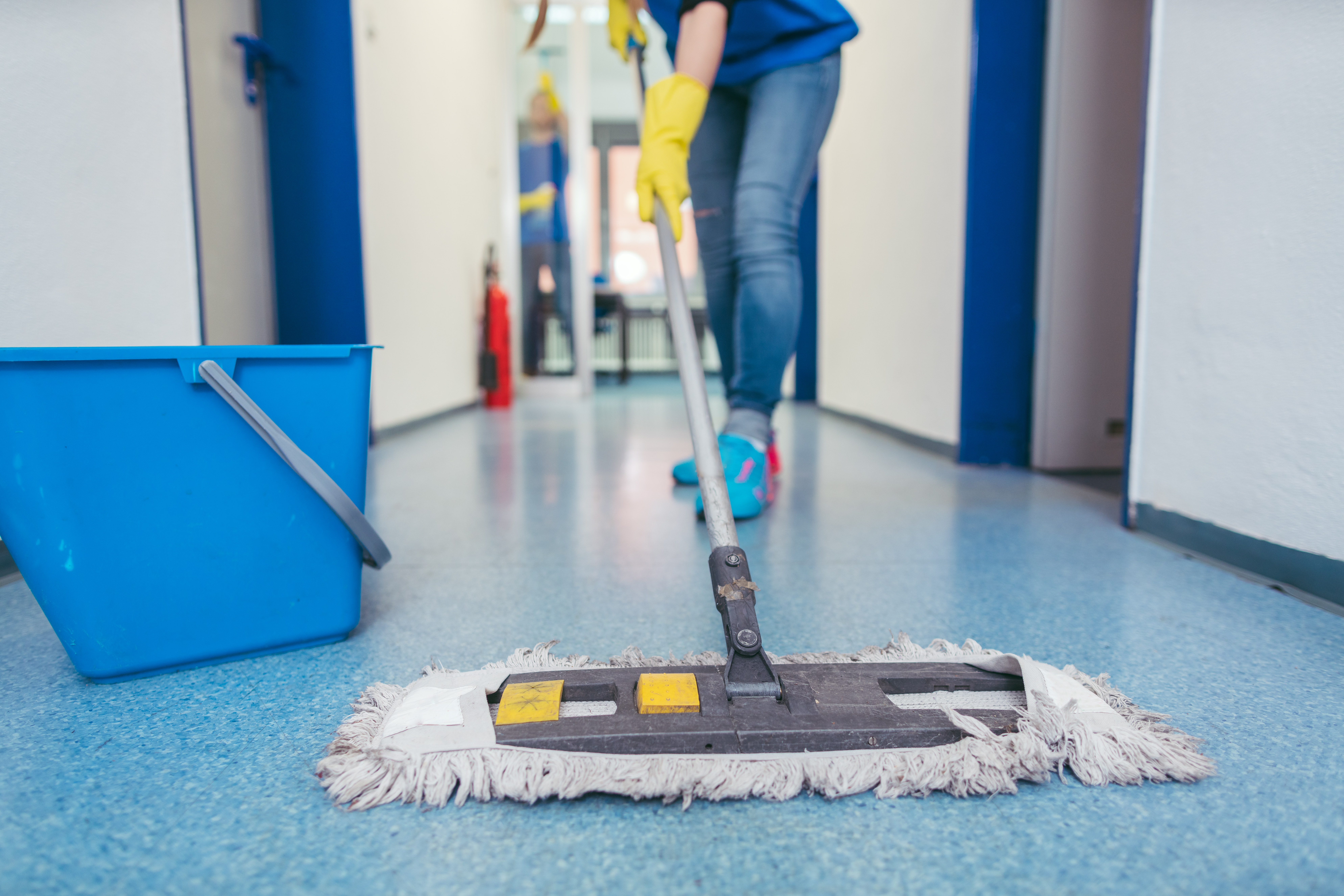 Cleaner mopping a medical facility corridor
